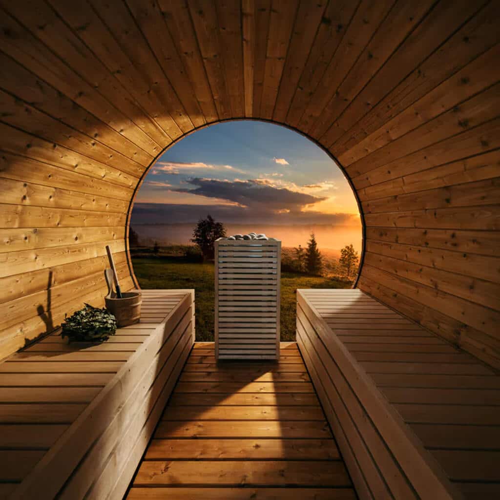 HUUM CORE sauna heater between wooden benches in a barrel sauna overlooking the sunset