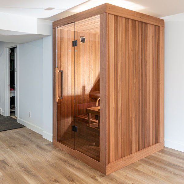 Element Nook indoor sauna with Thermo Grandis wood walls and a full glass front, viewed from the corner.